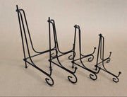 Four black metal display stands of varying heights arranged in a row to illustrate height