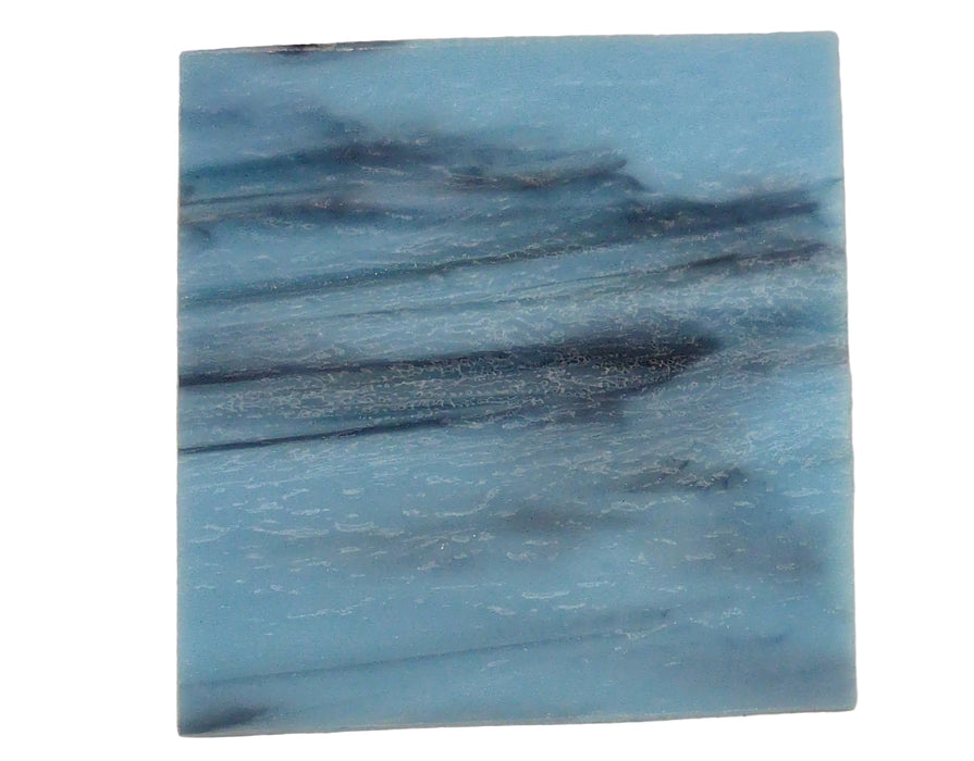 Two blue textured square samples on a beige surface with a green cutting mat background.